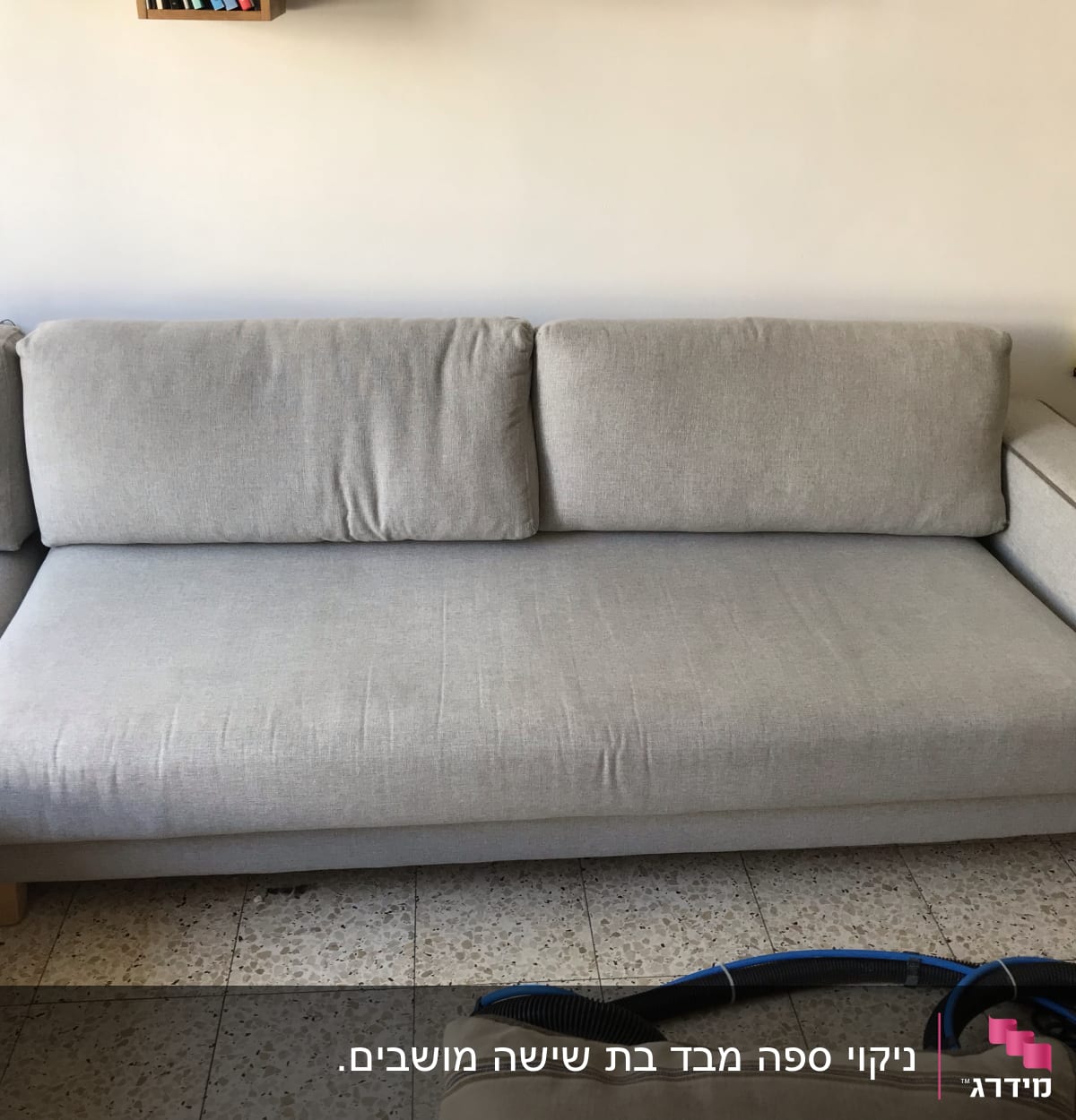 ספה אפורה עם צינור ניקוי על הרצפה